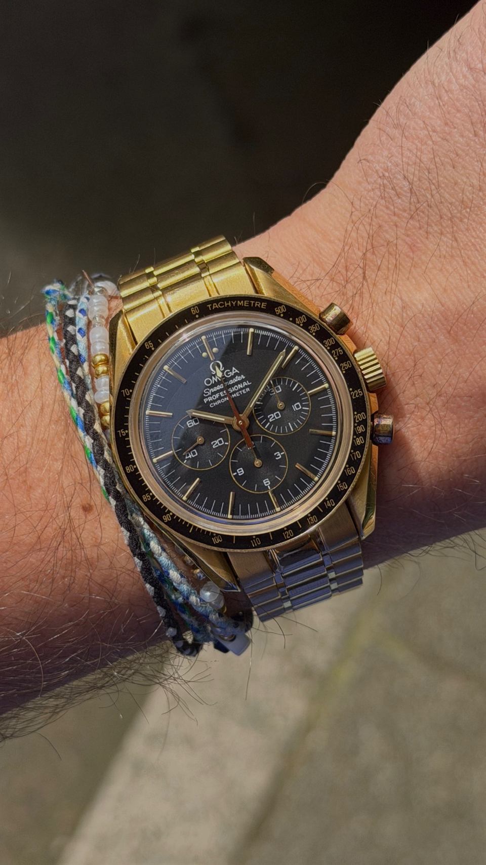 Omega Speedmaster mit Gehäuse und Band in Gold am Handgelenk.
