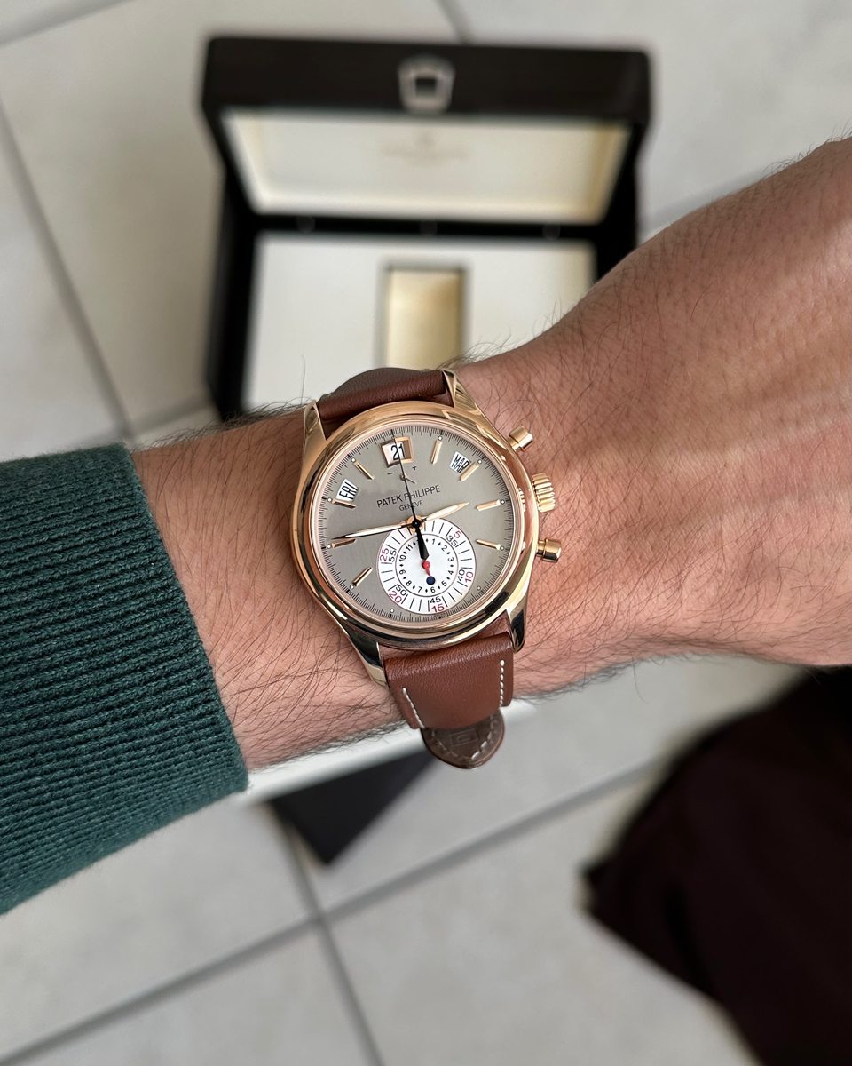 Patek Philippe Chronograph in Roségold mit hellem Zifferblatt am Handgelenk, dahinter die geöffnete Box