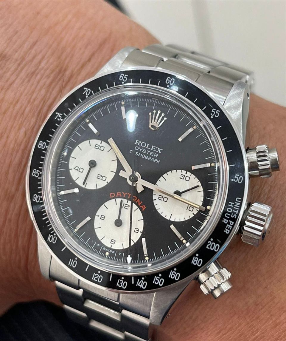 Ältere Rolex Daytona in Stahl mit schwarzer Lünette und rotem Daytona-Schriftzug am Handgelenk.