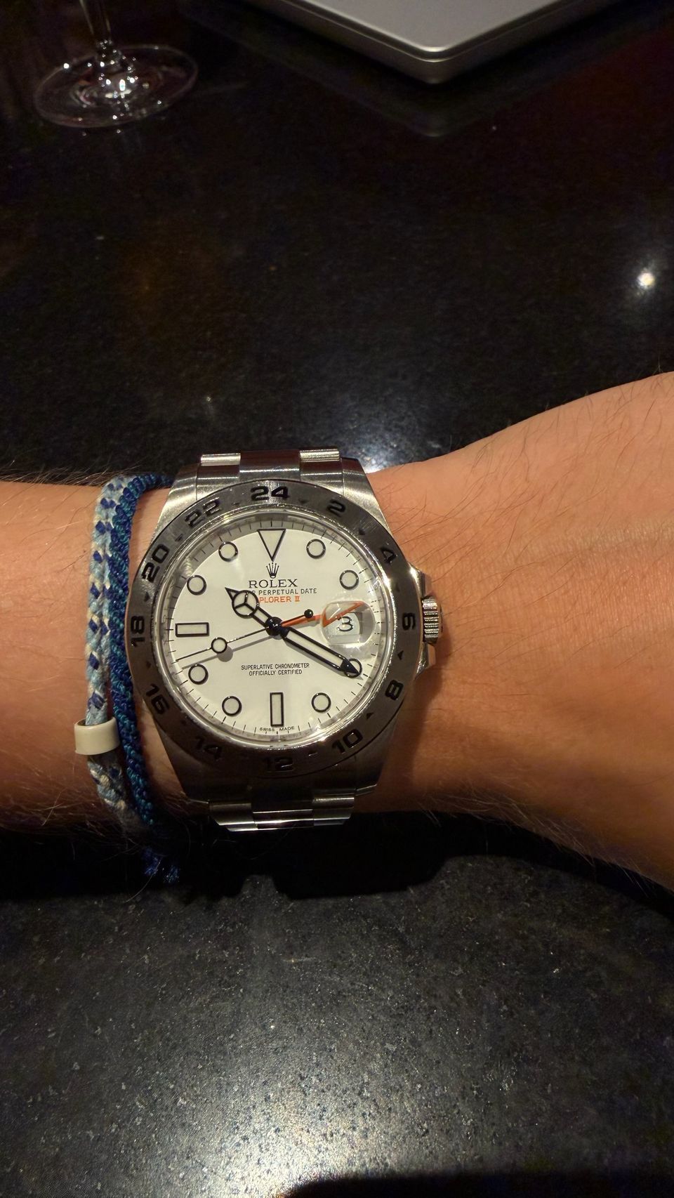 Rolex Explorer II in Stahl mit weißem Zifferblatt und orangem 24-Stunden-Zeiger am Handgelenk.